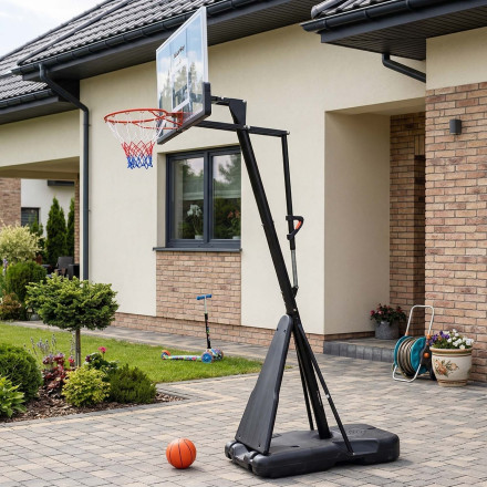 Mobilný basketbalový kôš Fuunky s čiernou konštrukciou a basketbalovou loptou na dlažbe pred rodinným domom
