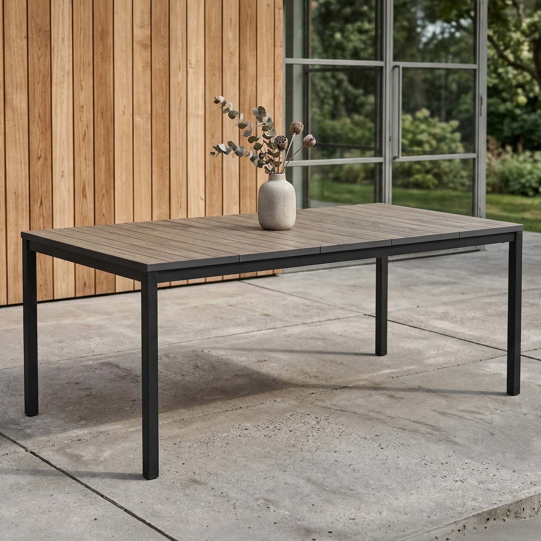 Záhradný jedálenský stôl Keter Deco Porto Nova vo farbe Black Walnut s vázou na terase pred drevenou stenou