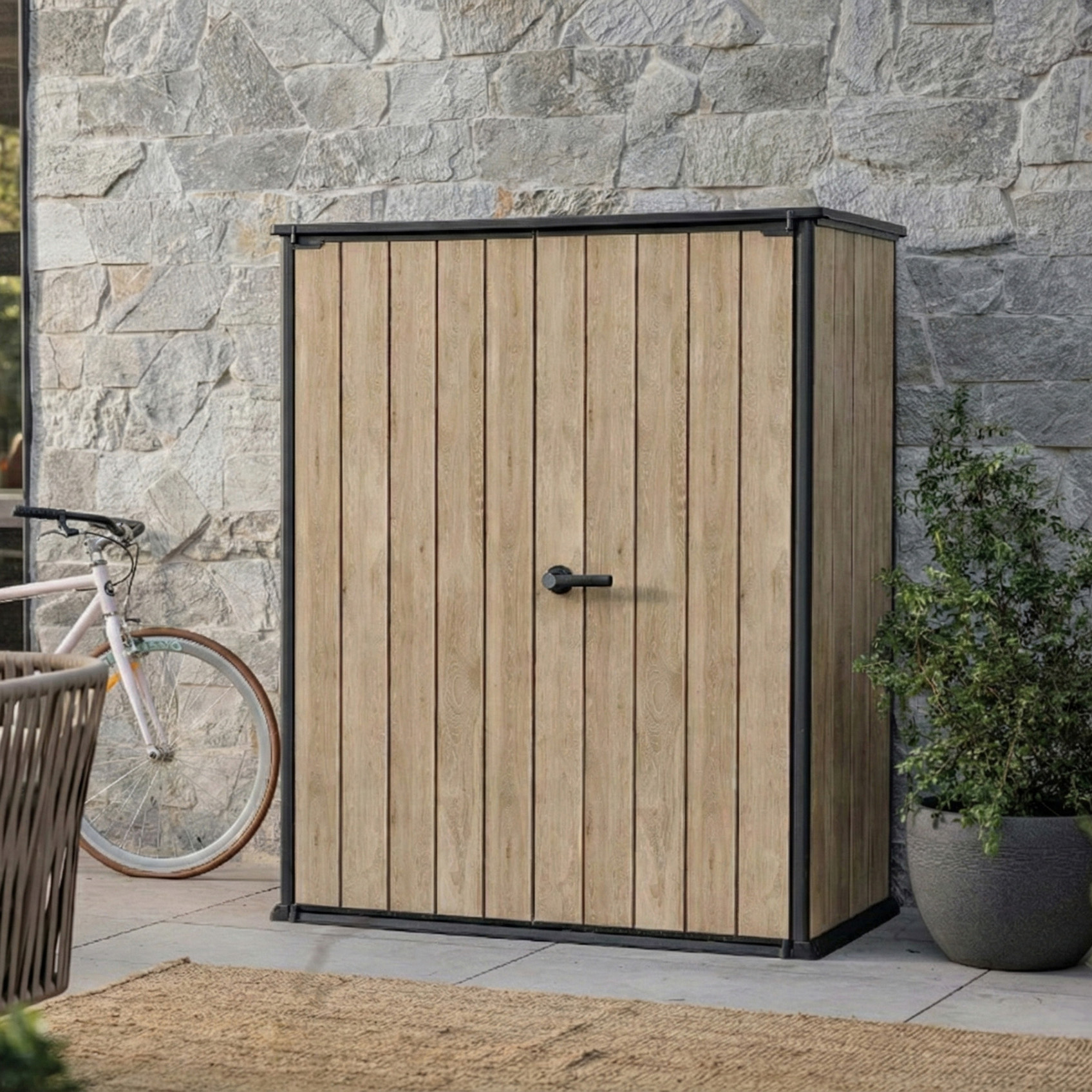 Záhradný sklad Keter Deco Vertical 1400L Ashwood vo svetlom drevenom dekore s čiernym rámom na terase