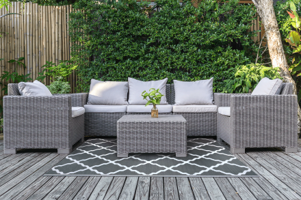 Záhradný koberec Middle Gray 180x270 cm MOODME s geometrickým vzorom umiestnený pod ratanovým záhradným nábytkom na terase