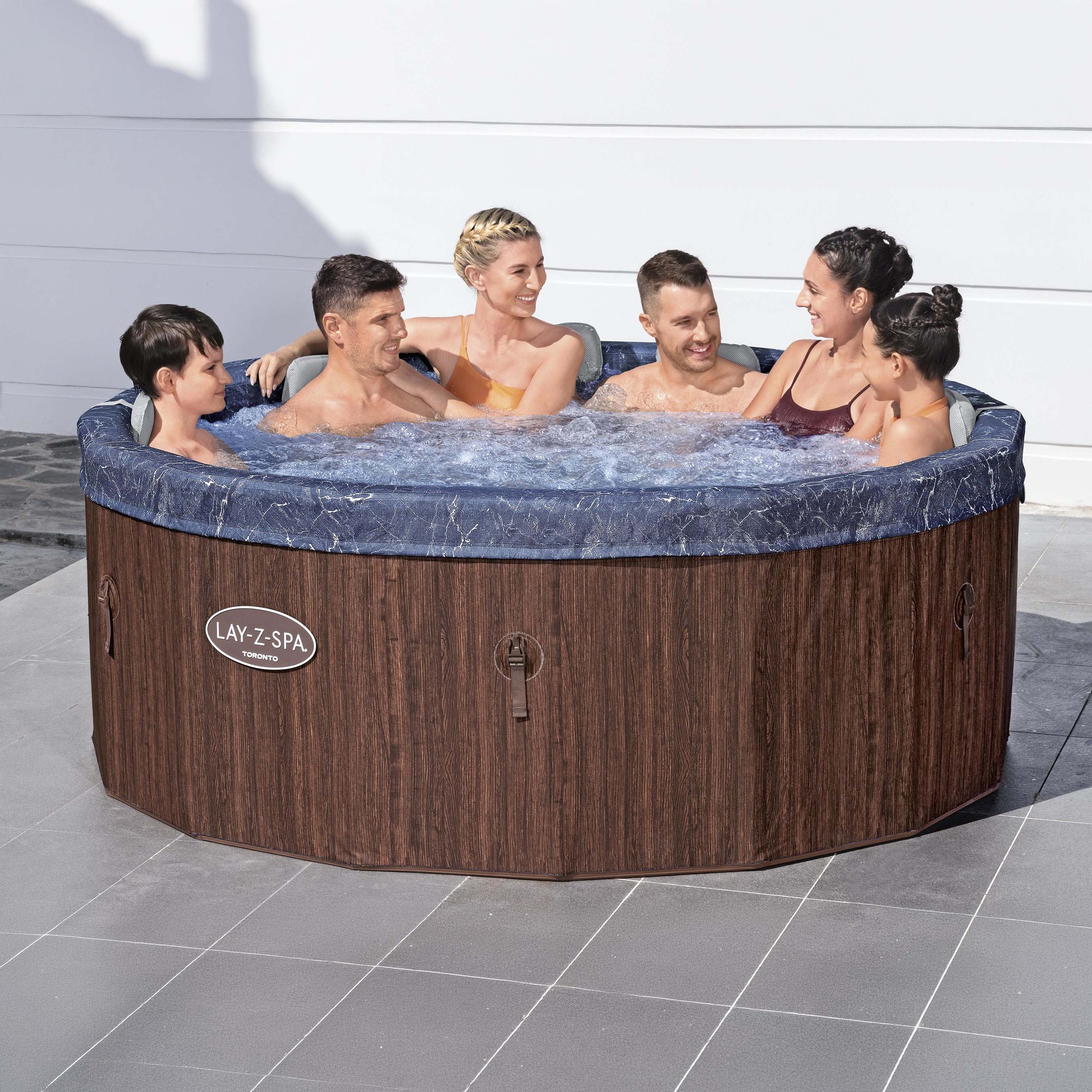 Skupina ľudí relaxujúca v okrúhlom záhradnom vírivom bazéne Lay-Z-Spa Toronto Smart AirJet s imitáciou tmavého dreva